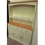 A cream painted pine kitchen dresser with a moulded cornice above a shelf with three drawers,