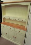 A cream painted pine kitchen dresser with a moulded cornice above a shelf with three drawers,