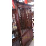 A reproduction mahogany standing corner cupboard of dished form with glazed cupboard doors and a