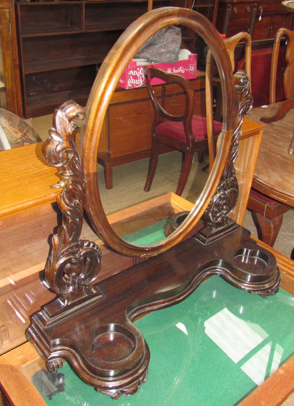 A Victorian style toilet mirror with an oval plate supported between carved uprights