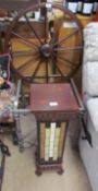 A ships wheel together with a metal coffee table and a floor lamp with multi-coloured glass panels