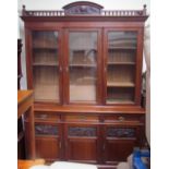 An Edwardian mahogany bookcase, with a carved spindle cornice above three glazed doors,
