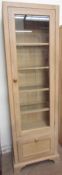 A modern limed oak display cabinet with a glazed door,