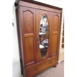 An Edwardian mahogany wardrobe, the moulded cornice above a central oval mirrored door,