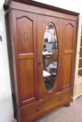 An Edwardian mahogany wardrobe, the moulded cornice above a central oval mirrored door,