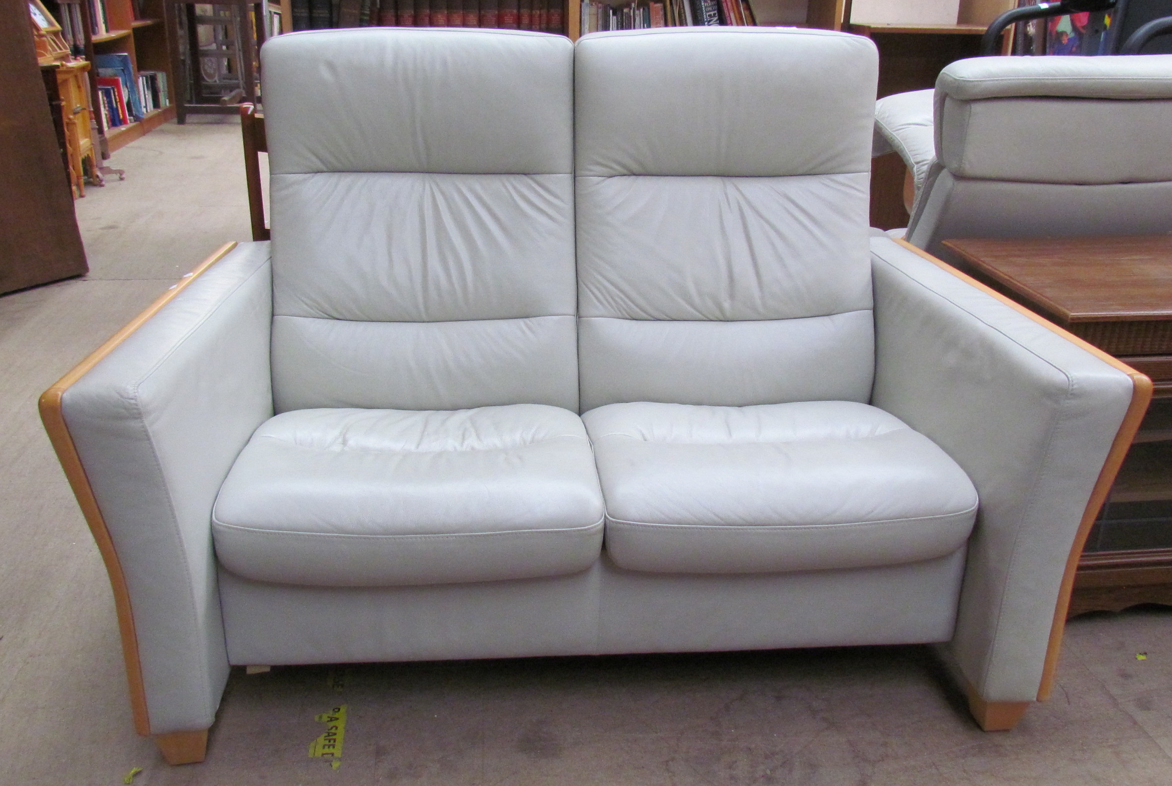 A green leather and beech upholstered two seater settee together with a pair of elbow chairs and