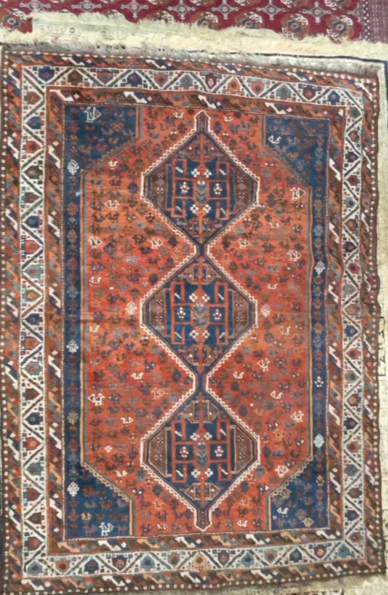 An orange ground rug with three interlocking medallions and multiple guard stripes,