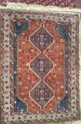 An orange ground rug with three interlocking medallions and multiple guard stripes,