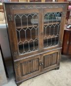 A 20th century oak bookcase with a rectangular top above a pair of leaded glazed doors and two