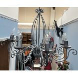 A scrolling grey metal eight branch chandelier