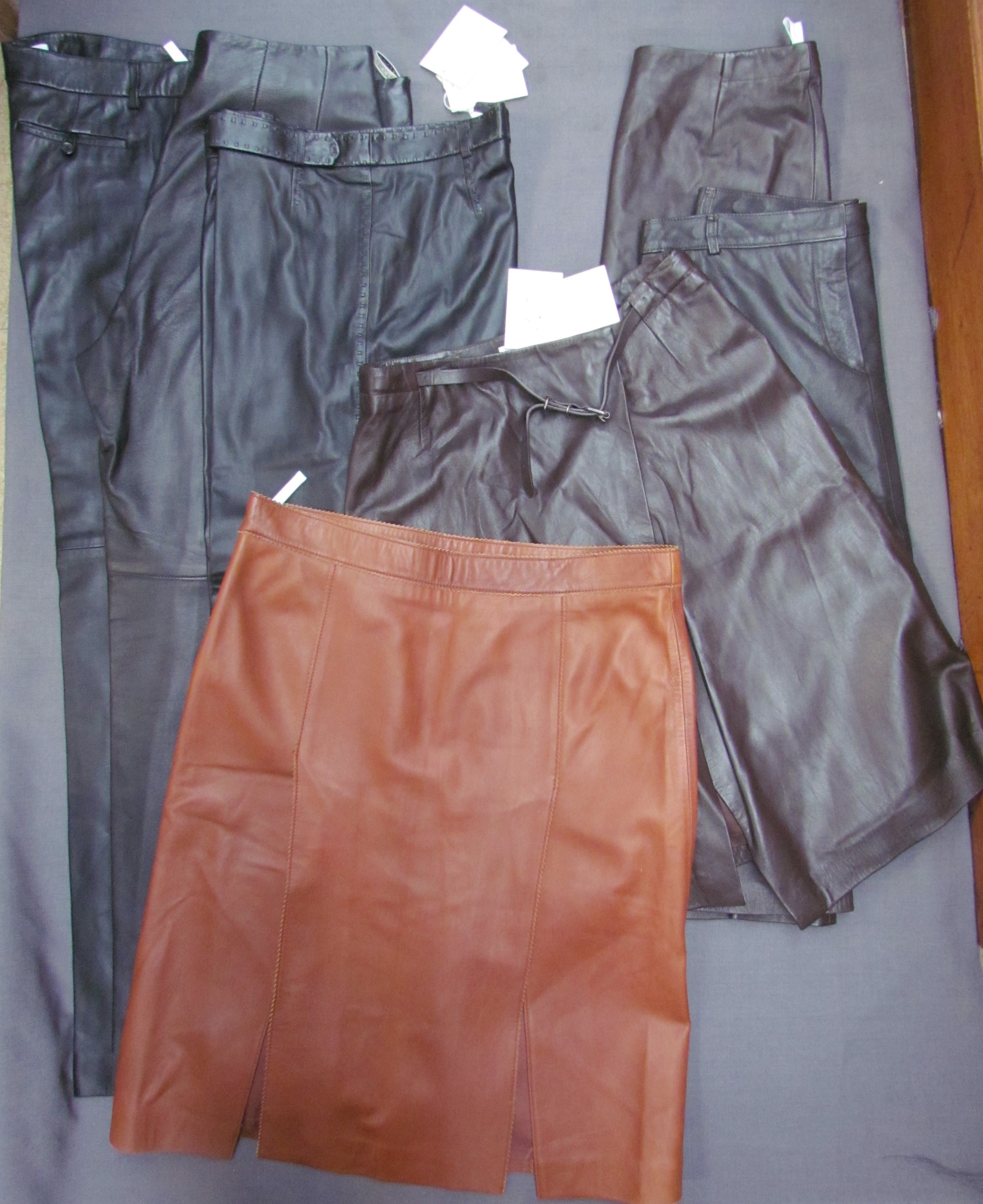 Three pairs of black leather trousers and four brown leather skirts by Nicole Fahri,