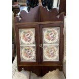 A 20th century hanging corner cupboard the doors inset with pottery tiles