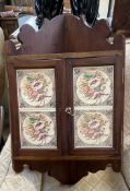 A 20th century hanging corner cupboard the doors inset with pottery tiles