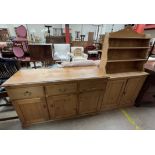 A small pine dresser the shaped back above two shelves and two cupboards on a plinth base,