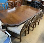 A George III style mahogany extending dining table with a shaped edge on twin pedestals and claw