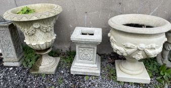 A reconstituted stone urn shaped planter decorated with swags of flowers together with another