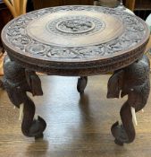 An early 20th century Indian carved occasional table of circular form on elephant head and trunk