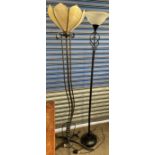 A wrought iron standard lamp with a leaf shaped glass shade and a flowing base together with a