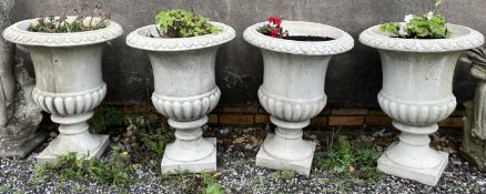 A set of four reconstituted stone urn planters with leaf moulded top on square bases