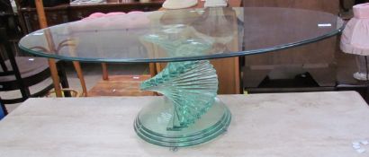 A modern glass coffee table of oval form on a stepped scrolling glass column and stepped circular