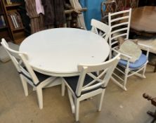 A modern extending dining table in white on a single pedestal together with a set of three dining