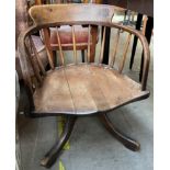 A 19th century horse shoe shaped chair with a spindle back and solid seat on a splayed base