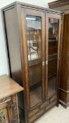 A 20th century mahogany effect display cabinet with glass doors and glass shelves above an