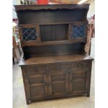 A 20th century oak dresser, the rack with a moulded cornice, shelves and a pair of glazed cabinets,