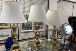 A set of three brass table lamps with baluster columns together with a magnifying mirror
