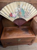 A carved Chinese camphor wood coffer together with a large painted fan