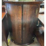 A mid 18th century oak hanging corner cupboard with a pair of mahogany crossbanded doors,