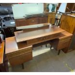 A mid 20th century teak dressing table with an arrangement of drawers on tapering legs