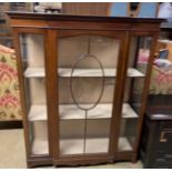 An Edwardian mahogany display cabinet with a breakfront top above a glazed door,