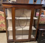 An Edwardian mahogany display cabinet with a breakfront top above a glazed door,