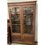 A 20th century oak bookcase with a moulded cornice above leaded glazed doors and cupboards to the