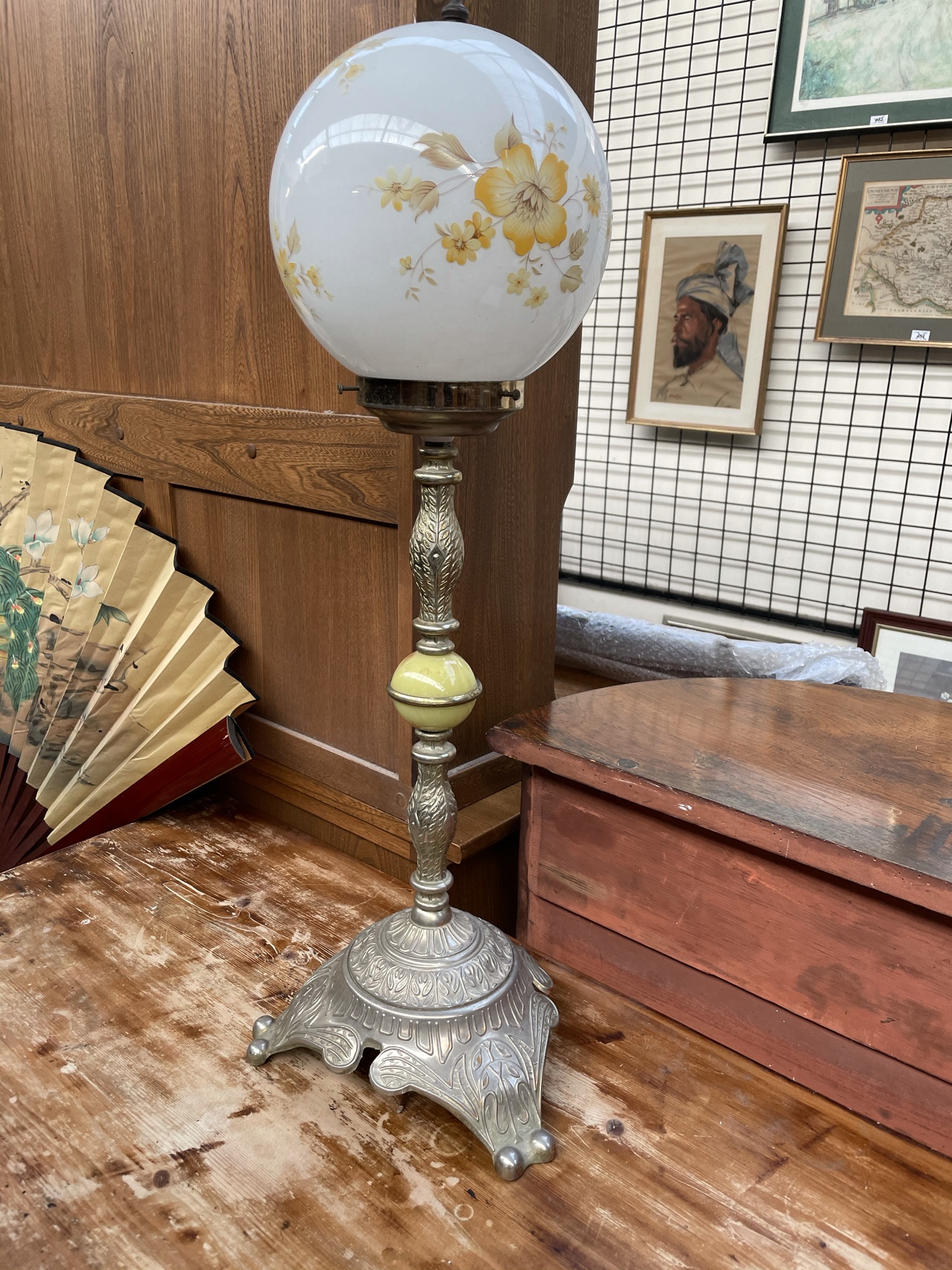 A table lamp with an opaque glass shade on a metal column