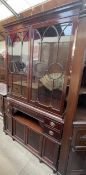 A reproduction mahogany bookcase with a moulded cornice above a pair of glazed doors,