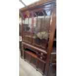 A reproduction mahogany bookcase with a moulded cornice above a pair of glazed doors,