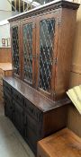 A 20th century oak dresser, the moulded cornice above three leaded glazed doors,