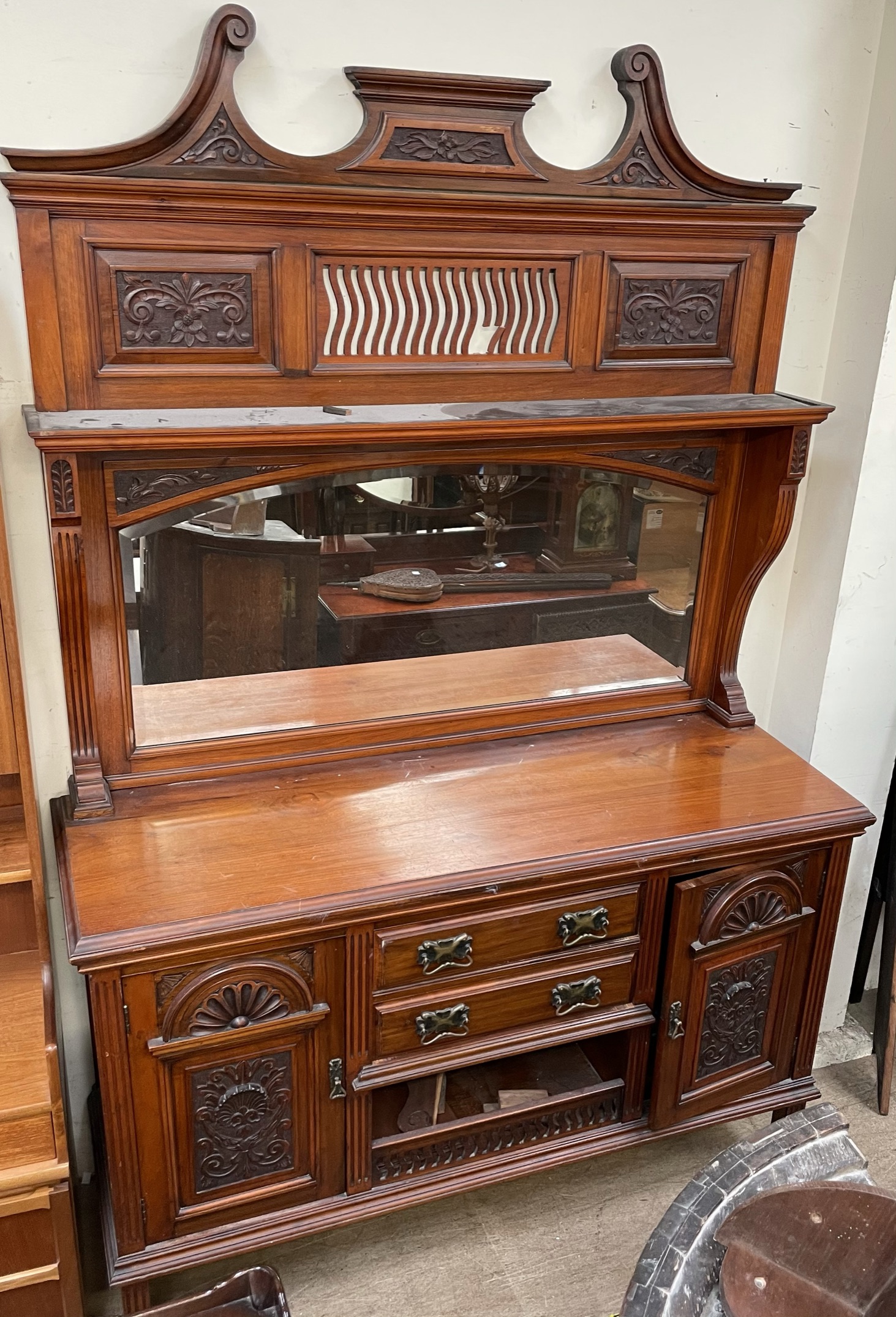 An Edwardian walnut mirrorback sideboard, with a carved cresting, shelf and arched mirror,