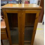 A modern pine side cabinet with a pair of glazed doors