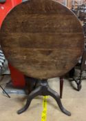 A 19th century oak tripod table with a circular top on a baluster column and tripod base