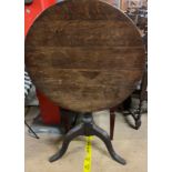 A 19th century oak tripod table with a circular top on a baluster column and tripod base