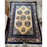 A Chinese rug with a golden ground and circular scrolling floral decoration to blue bands