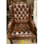 A brown leather button back upholstered wing back elbow chair