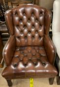 A brown leather button back upholstered wing back elbow chair