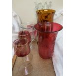 A cranberry glass trumpet shaped lamp shade together with ruby glass drinking glasses,