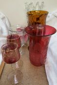 A cranberry glass trumpet shaped lamp shade together with ruby glass drinking glasses,