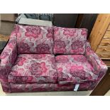 A floral decorated two seater sofa bed