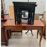 A reproduction mahogany desk with a shaped top on tapering legs together with an ebonised nest of